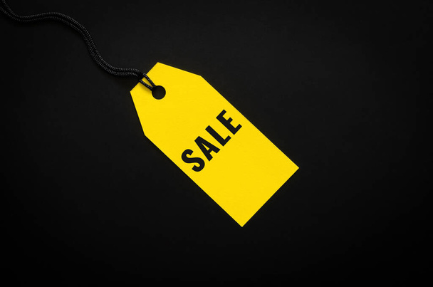 Una etiqueta de precio de venta amarilla en el fondo negro para ir de compras y descuento en el concepto de Viernes Negro. - Foto, imagen