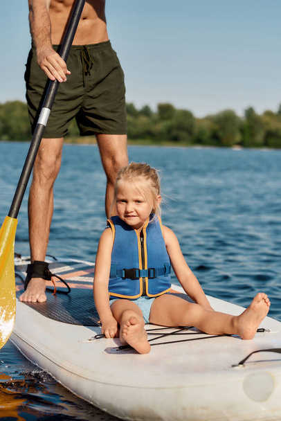 Father riding his little girl on kayak in lake - Photo, Image