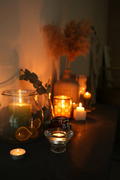 Zářící vonné svíčky na stole v tmavé místnosti - Fotografie, Obrázek