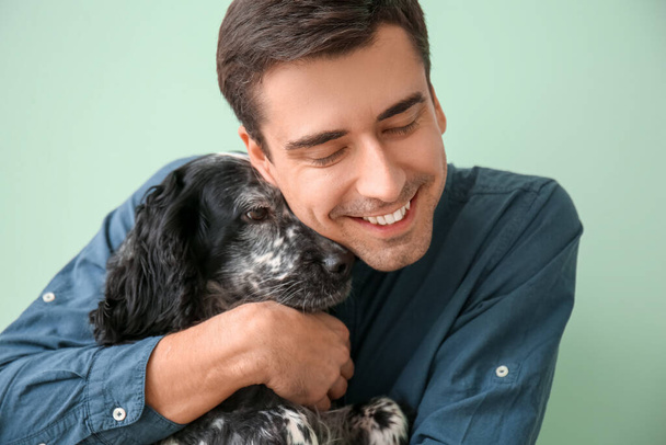 Щасливий молодий чоловік з милою собакою на кольоровому фоні
 - Фото, зображення