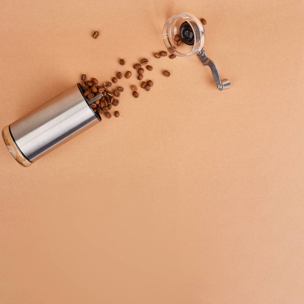 Ręczna szlifierka do kawy i palone ziarna kawy na pastelowym tle. Widok góry. Przestrzeń kopiowania - Zdjęcie, obraz