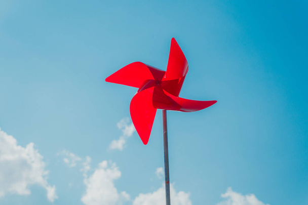 красная ветряная мельница на фоне неба и облаков - Фото, изображение