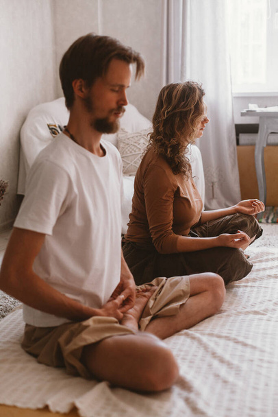 A vertical shot of a young couple doing yoga and meditating together - Fotoğraf, Görsel