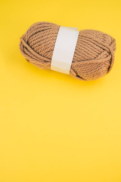 A vertical shot of isolated beige yarn on yellow background with text space - Fotoğraf, Görsel