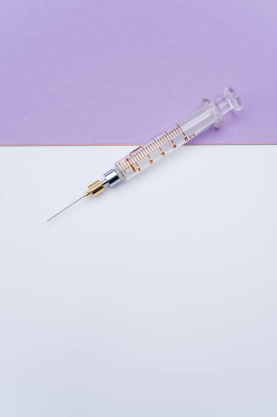 an isolated injection syringe on mauve paper background with text space - Foto, afbeelding