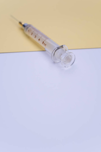 an isolated injection syringe on yellow and white paper background with text space - Photo, image