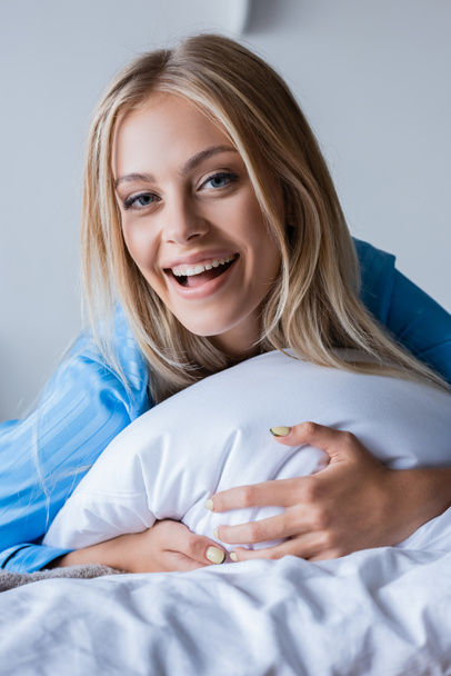amazed blonde woman lying on pillow in bedroom  - Foto, afbeelding