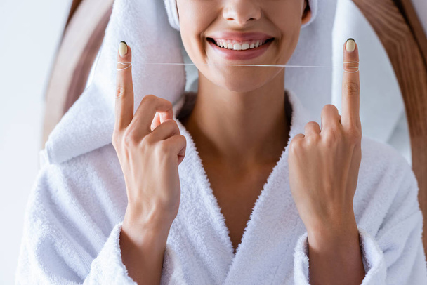 partial view of happy woman holding dental floss in bathroom - Foto, Bild