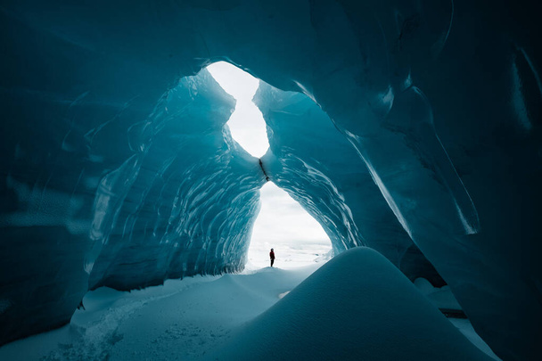 Kışın İzlanda 'nın Vatnajkull buzulunda güzel bir buz mağarasında duran insan. - Fotoğraf, Görsel
