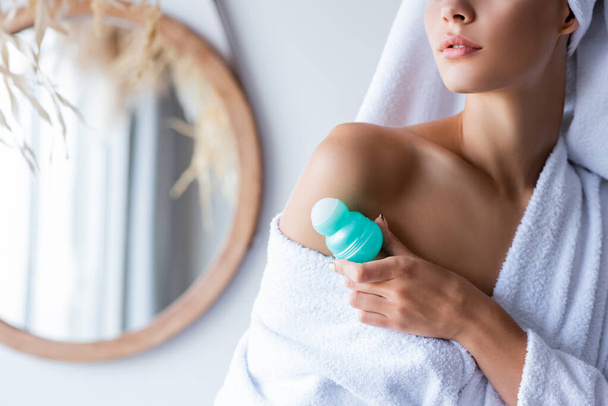 vista recortada de la mujer joven sosteniendo rollo desodorante en el baño  - Foto, Imagen