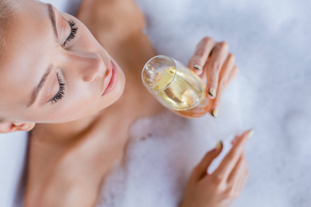 vista superior da mulher tomando banho e segurando copo de champanhe  - Foto, Imagem