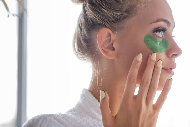 Bornozlu genç bir kadın yeşil göz bandı takıyor. - Fotoğraf, Görsel
