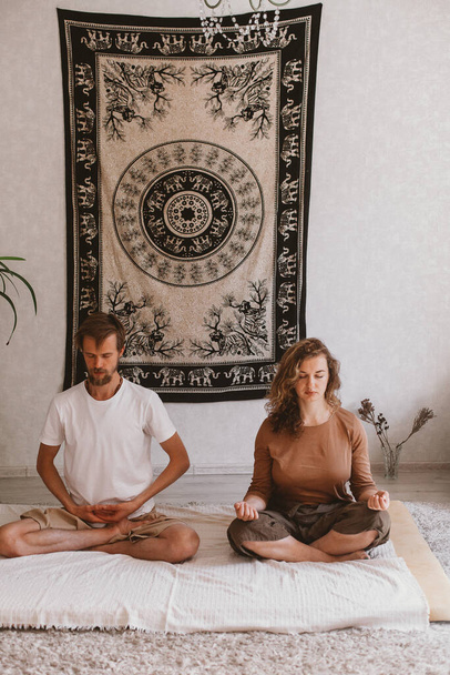 Pionowe ujęcie młodej pary uprawiającej jogę i medytującej razem - Zdjęcie, obraz