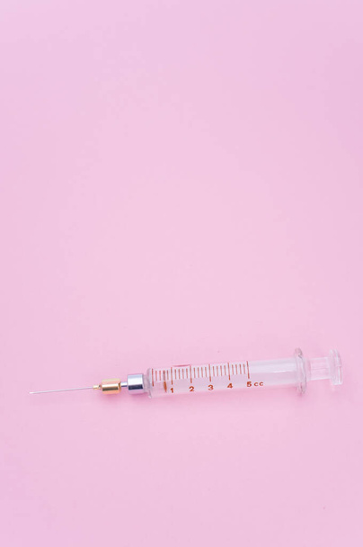 an isolated injection syringe on mauve paper background with text space - Foto, afbeelding