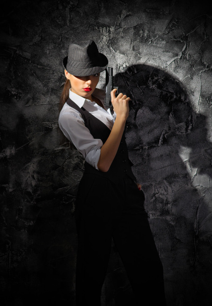Woman with hat and gun on grey wall - Foto, Imagem