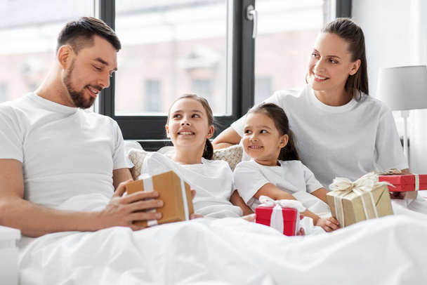 happy family with christmas gifts in bed at home - Fotografie, Obrázek