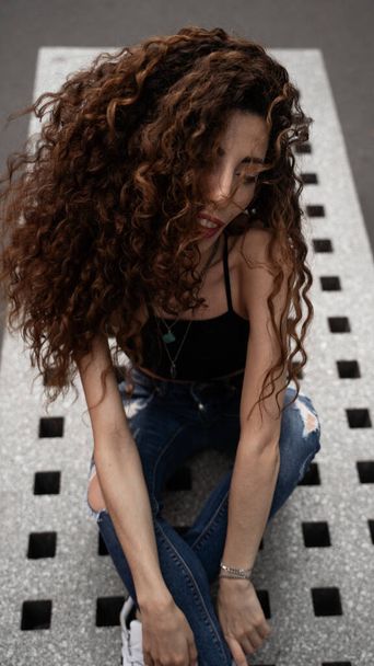 A vertical shot of a sexy Caucasian woman with curly hairs - Zdjęcie, obraz