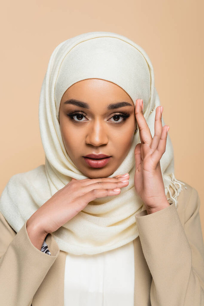 Portrait of young muslim woman in hijab with makeup isolated on beige  - Foto, imagen