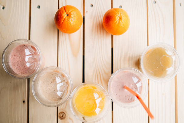 Uma vista superior de um smoothie em copos takeaway formou um rosto sorridente com laranjas frescas como olhos - Foto, Imagem