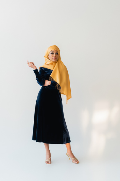 full length of muslim woman in hijab and velvet blue dress on white - Foto, afbeelding