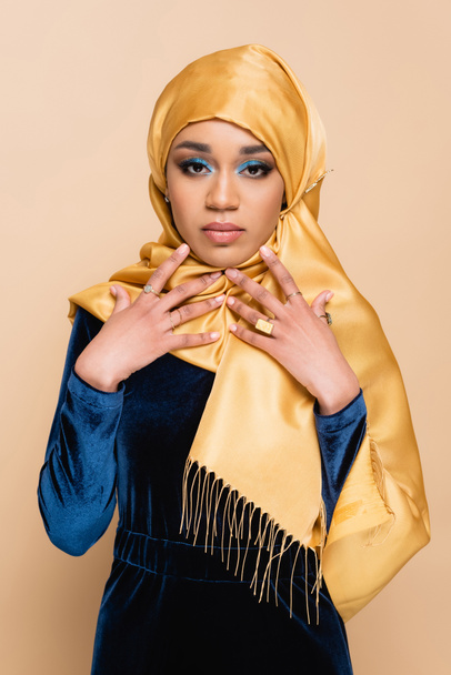 young muslim woman in hijab and velvet blue dress isolated on beige  - 写真・画像