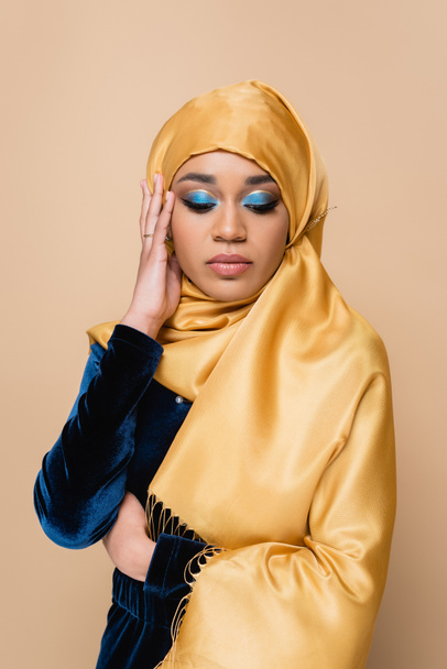 muslim woman in hijab with bright eye shadow isolated on beige - Foto, imagen