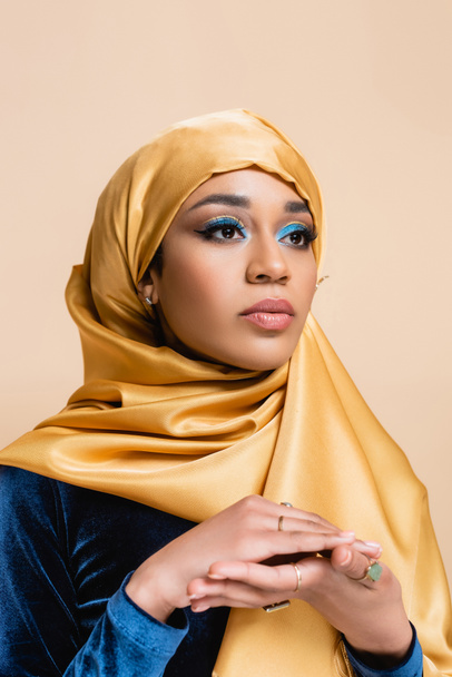 young muslim woman in hijab with bright makeup posing isolated on beige - Фото, изображение
