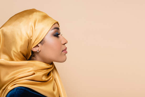 Profil einer muslimischen Frau im gelben Hijab mit hellem Make-up isoliert auf beige - Foto, Bild