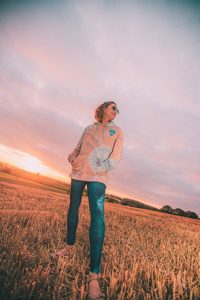 A beautiful shot of a caucasian female wearing a colorful alien hoodie posing in a field - Fotoğraf, Görsel