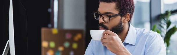 Gestionnaire afro-américain tenant une tasse de café près de l'ordinateur, bannière  - Photo, image
