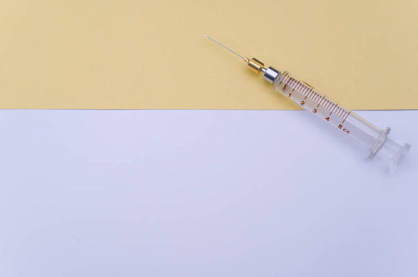 an isolated injection syringe on yellow and white paper background with text space - Photo, Image