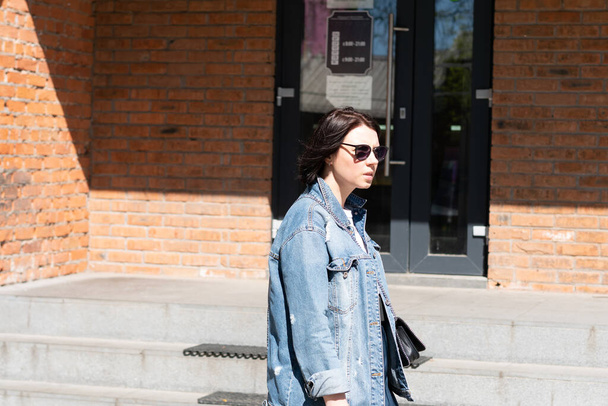 молодая красивая женщина позирует в джинсовой куртке снаружи - Фото, изображение