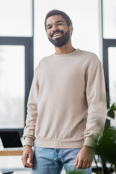 Young african american businessman in casual clothes smiling at camera in office  - Zdjęcie, obraz