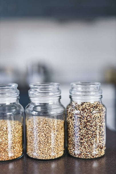 キノアレンズ豆などの穀物やマメ科植物の異なる明確なパントリー瓶台所のボケとベンチ上にソバや大麦,シンプルな成分の概念 - 写真・画像