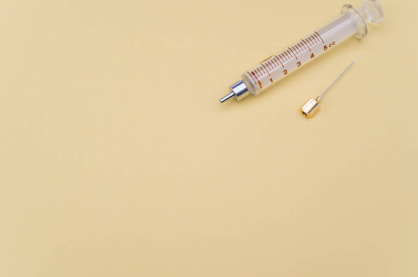 an isolated injection syringe on yellow paper background with text space - Foto, Imagen