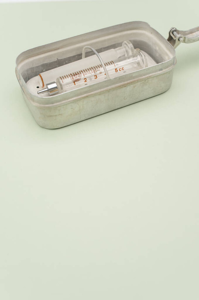 an isolated injection syringe and needles in a box  on green paper background with text space - Foto, imagen