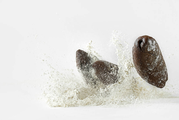 Minimalistic picture - rye bread falling into flour on a white background - Foto, Bild