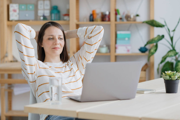 uma mulher europeia em seu escritório em casa está trabalhando com um laptop ou assistindo a um webinar - Foto, Imagem