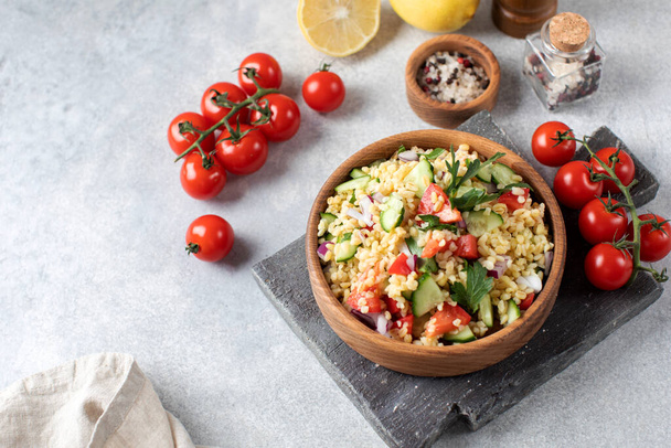 Salad with bulgur, tomatoes, cucumbers and parsley. Tabouleh dish. Oriental cuisine. Copy space. - Φωτογραφία, εικόνα