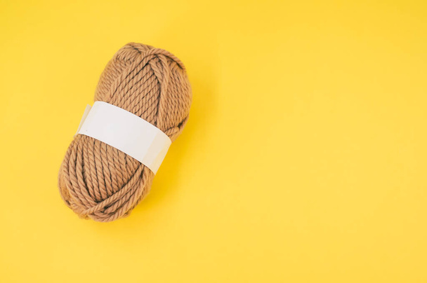 A vertical shot of isolated beige yarn on yellow background with text space - Fotó, kép