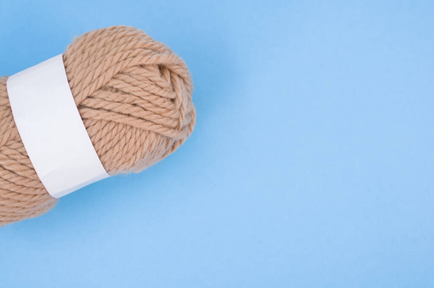 A vertical shot of isolated beige yarn on blue background with text space - Zdjęcie, obraz