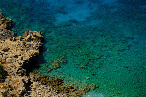 An aerial shot of blue water on the rocky shore - Zdjęcie, obraz