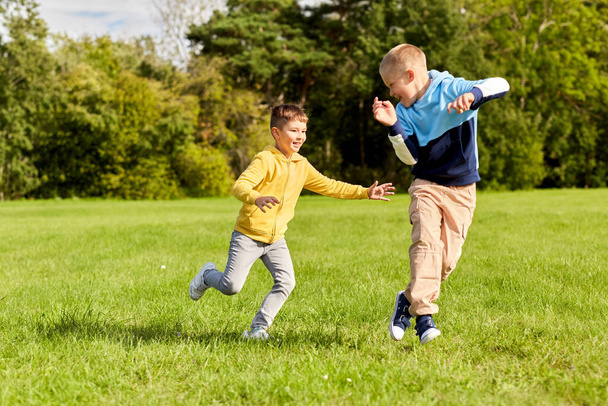 two happy boys playing tag game at park - Foto, Imagen