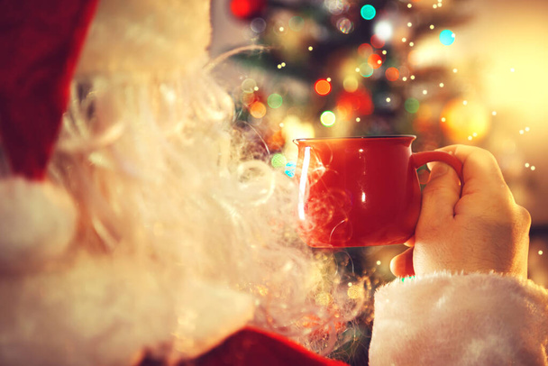 Authentic Santa Claus is drinking hot chocolate. Home interior, Christmas decorations. New Year and Christmas concept.  - Zdjęcie, obraz