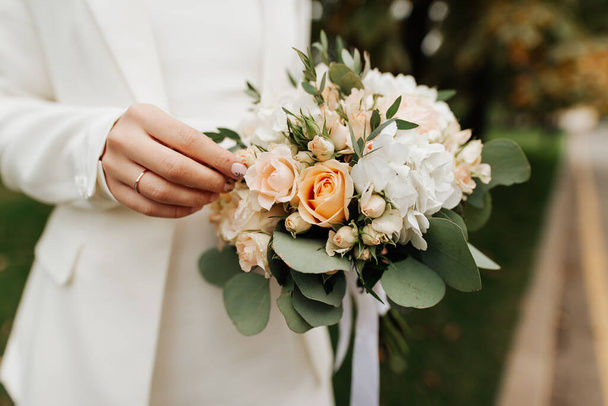 stylish bride in a white dress and manicure holding a wedding bouquet - Фото, зображення