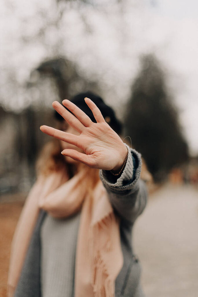 stylish girl walks on the street and covers her face with her palm - Photo, Image