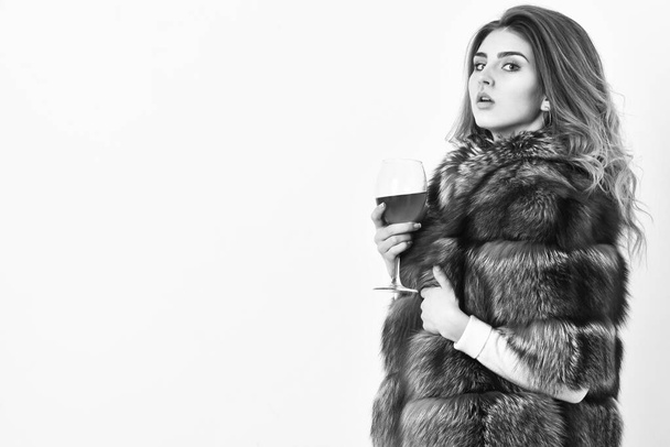 Wine culture concept. Reasons drink red wine in wintertime. Woman drink wine. Girl fashion makeup wear fur coat hold glass alcohol. Elite leisure. Lady fashion model curly hairstyle enjoy elite wine - Foto, immagini