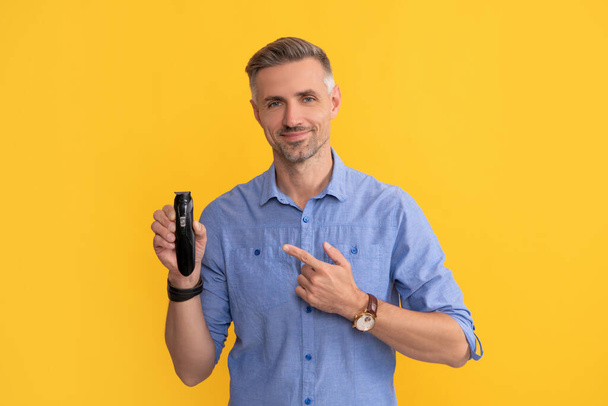 τύπος που δείχνει ηλεκτροφόρο ξυριστικό σε κίτρινο φόντο, ξυρισμένη - Φωτογραφία, εικόνα