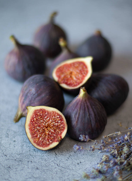 Fig fruits, whole and halves, and a branch of lavender on a gray background.  - Photo, Image