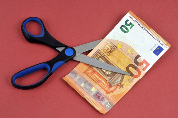 50 notas de euro cortadas com tesoura close-up sobre fundo vermelho - Foto, Imagem